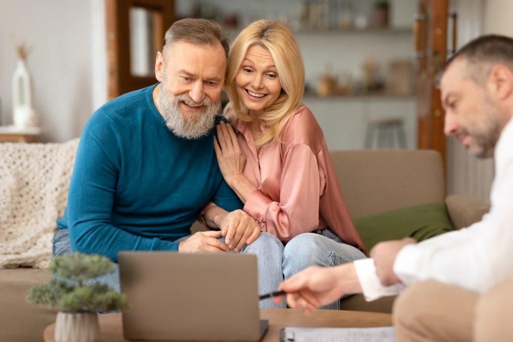 Male Consulting Senior Couple Showing Laptop Selling Real Estate Indoor